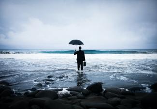 Un homme en costard tient un parapluie dans la mer