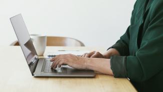 Une femme s'apprête à taper à l'ordinateur assise à un bureau